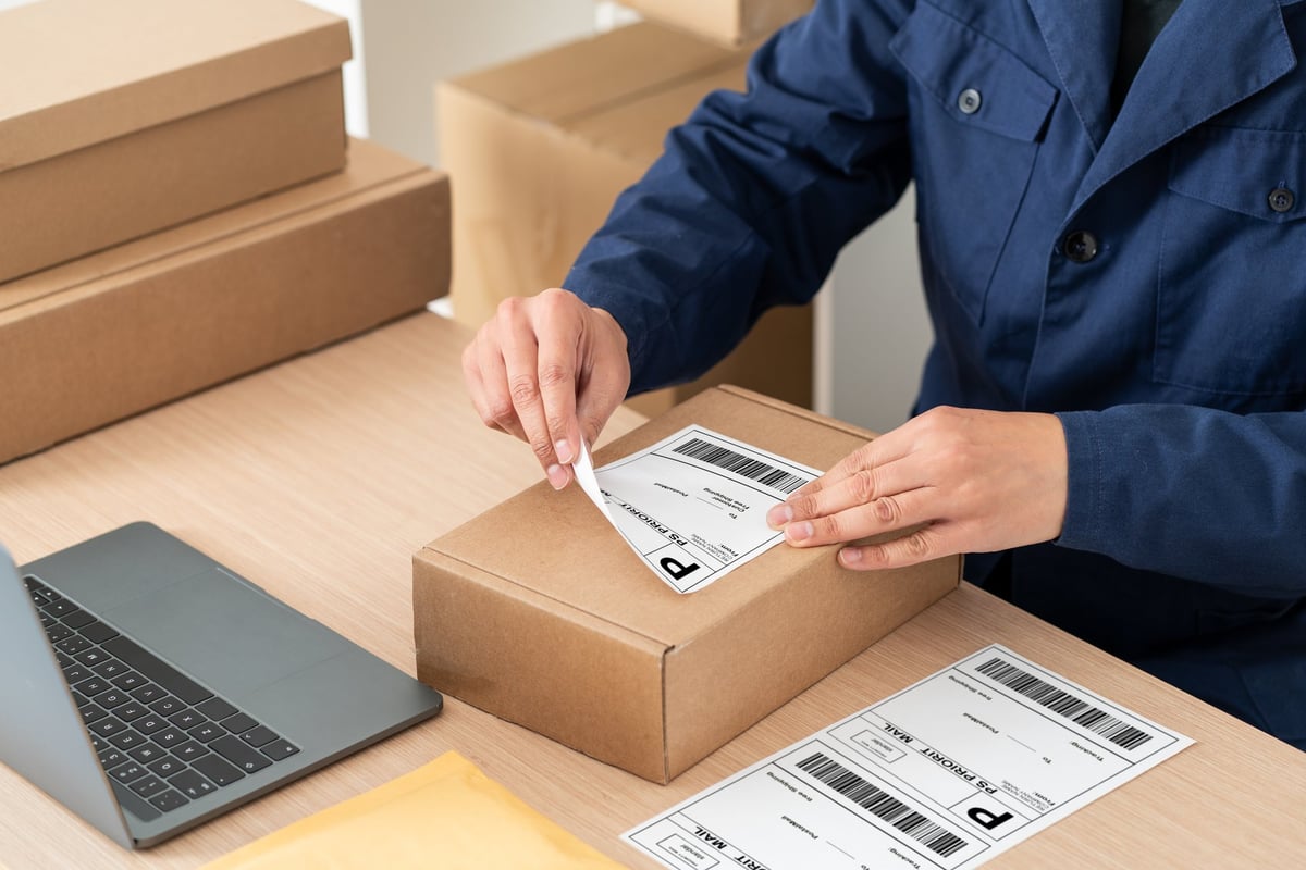 Persona colocando una guía de envío en una caja de cartón