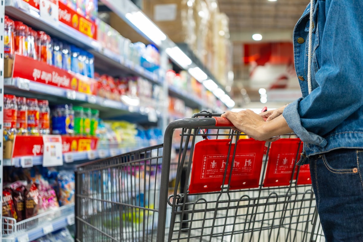 Compradora empujando un carrito en un pasillo de tienda